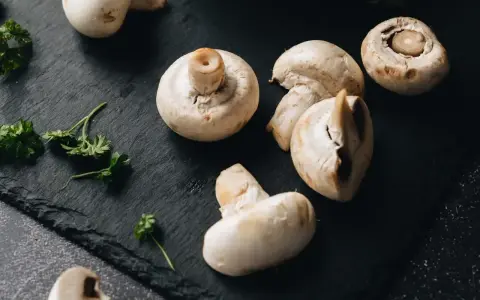 Świeże pieczarki na czarnej desce. Zastanawiasz się, czy pieczarki można mrozić? Tak, można je mrozić, zachowując ich smak i aromat.