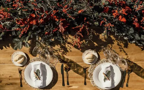 Decoración festiva para una boda en diciembre. Mesa de madera con ramas de pino, bayas rojas y detalles rústicos.