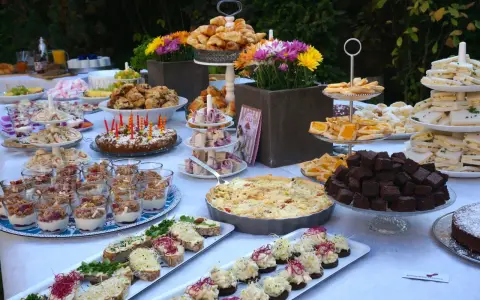 Ein üppiges Brunch Buffet im Freien mit Croissants, Quiche, Brownies, Sandwiches und süßen Leckereien.