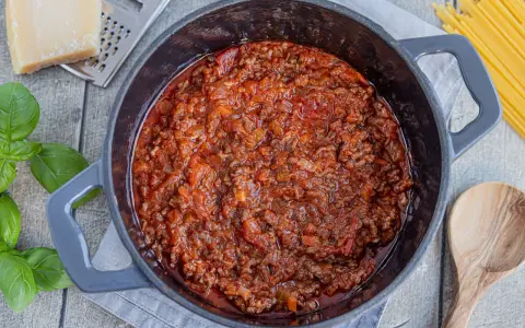 Herzhafte, beste Bolognese original im Topf, mit frischem Basilikum, Parmesan und Spaghetti daneben.