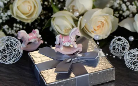 En rosa gungstol på en silverfärgad present. En fin dopfika blått med vita rosor i bakgrunden.