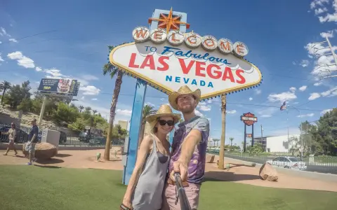 Para co przywieźć ze Stanów? Pamiątkę z Las Vegas! Uśmiechnięta para pozuje do selfie pod słynnym znakiem.