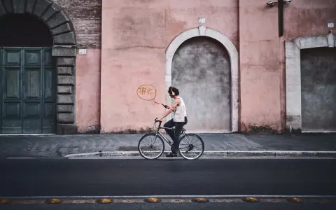 Un ciclista con cuffie ascolta musica mentre pedala, un'istantanea dal reportage di un tour urbano.