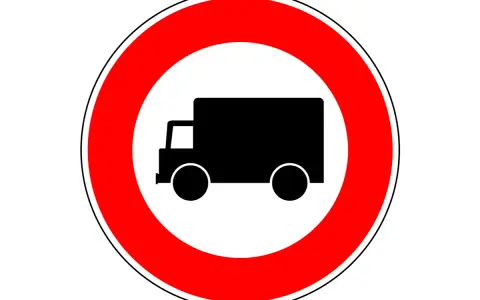 Znak drogowy: zakazy dla ciężarówek. Czerwone koło z czarnym symbolem ciężarówki w środku.