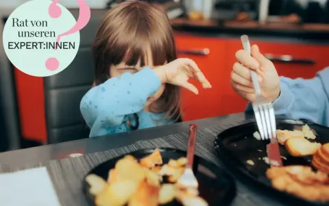 Kind mit blauer Kleidung weint, während es isst. Ein Teller mit Kartoffeln und Fleisch. Hilfe bei picky eater syndrom.