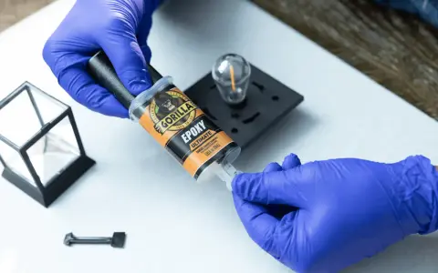 Gloves prepare to apply Gorilla Epoxy, known for its incredible strength, to a small glass and metal object.