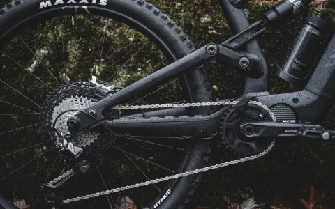 Część roweru elektrycznego z napędem **Shimano EP8** w deszczu. Widoczna kaseta, przerzutka, łańcuch i korba.