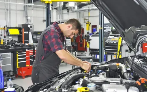 Mecánico trabajando en un motor en un taller. El sistema ERP del taller está organizado y listo para el diagnóstico.