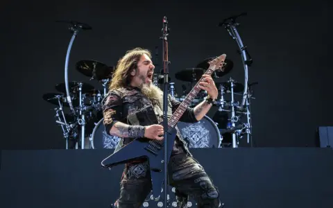 Robb Flynn z Machine Head na jednym z koncertów, w pełni energii, szaleje na czarnej gitarze typu V.