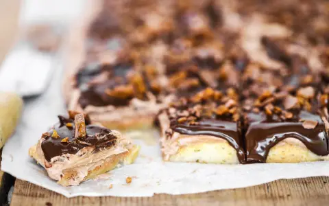 En chokladkaka i långpanna med fluffig chokladkräm och glansig chokladglasyr, toppad med krossad choklad och bitar av godis.