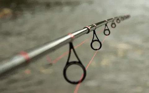 Idealny spinning na szczupaka z brzegu, z pomarańczową żyłką przechodzącą przez przelotki.