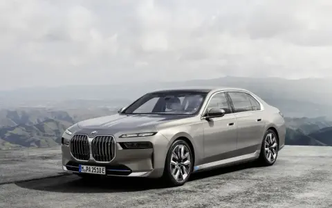 Eleganckie, srebrne BMW 7 2025 z niebieskimi akcentami na felgach, zaparkowane na tle górskiego krajobrazu.