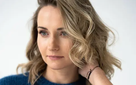Zuzanna Irena Grabowska z burzą blond włosów i niebieskimi oczami, w granatowym swetrze.