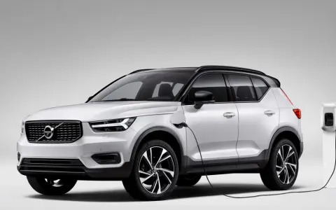 Biały Volvo XC40 Recharge plug-in hybrid podłączony do ładowarki.