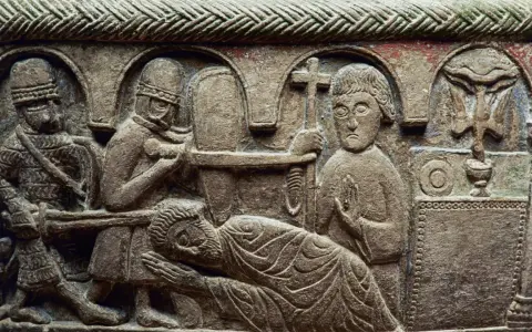 Detaljerad stenrelief från medeltiden konst visar en dramatisk scen med soldater och en liggande figur. En man håller ett kors.