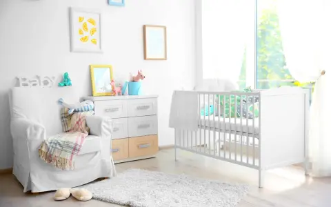 Stanza luminosa con lettino bianco, poltrona comoda e decorazioni a tema neonato. Un nido accogliente per un piccolo tesoro.