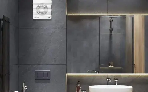 Extractor de baño blanco instalado en pared de azulejos grises.