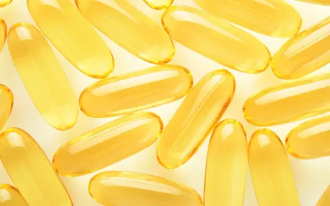 Żółte kapsułki omega 3 ułożone na jasnym tle. Kiedy brać omega 3? Najlepiej po posiłku, by zwiększyć wchłanianie.