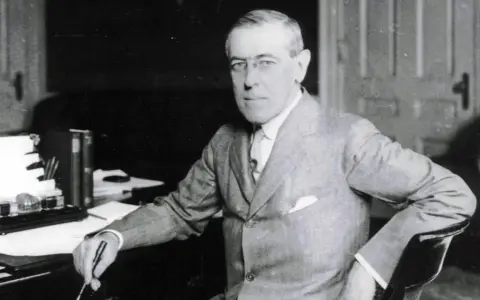 Woodrow Wilson, der den 14-Punkte-Plan zur Friedenssicherung nach dem Ersten Weltkrieg entwickelte, sitzt an seinem Schreibtisch.