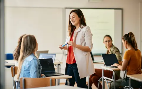 Nauczycielka wyjaśnia studentom, jak zostać nauczycielem, prowadząc lekcję w sali komputerowej.