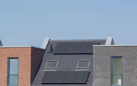 Nowoczesne dachy z panelami fotowoltaicznymi, które zapewniają zieloną energię. Domy z cegły i dachówką, z oknami dachowymi.
