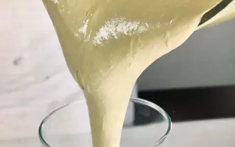 Versando una soffice pate a bombe in un bicchiere trasparente, pronta per una deliziosa preparazione.