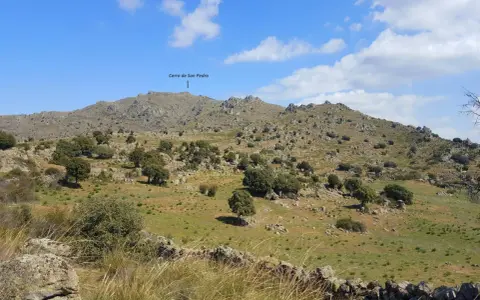 Paisaje rocoso y verde con el **cerro de San Pedro** en Colmenar Viejo al fondo.