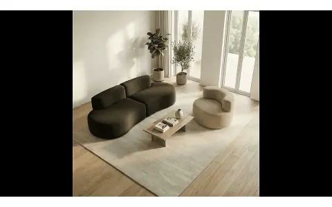 Un salon moderne avec un canapé incurvé marron chocolat et un fauteuil rond beige, une table basse en bois et un tapis clair.