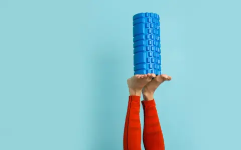 Beine in der Luft, ein blauer Faszienroller balanciert auf den Füßen. Ein Zeichen für das effektive Faszien entgiften und Regeneration.