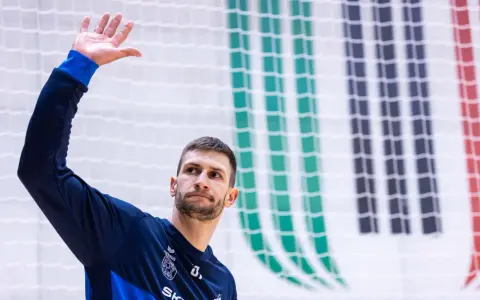 Michał Przybylak wita kibiców, unosząc dłoń.