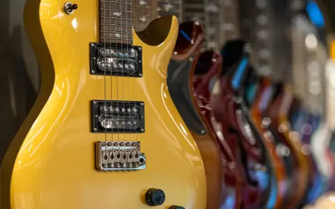 Guitarra eléctrica dorada con pastillas de **single coil** en primer plano, seguida de otras guitarras de colores.
