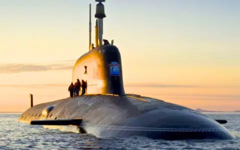 Un imposant sous-marin, potentiellement le sous-marin le plus puissant du monde, navigue sur une mer calme au coucher du soleil.