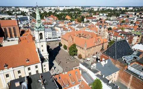 Widok na rynek i zabytkowe budynki Torunia, jednego z obiektów UNESCO w Polsce. Widać Ratusz Staromiejski i wieżę kościoła.