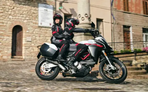 Para jadąca na sportowym motocyklu Ducati przez urokliwe, brukowane uliczki.