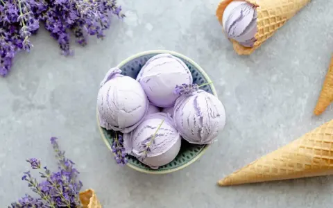 Schalen und Waffelkegel mit cremigem Lavendeleis, garniert mit frischen Lavendelzweigen.