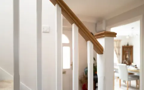 Barandilla de escalera blanca con pasamanos de madera, ideal para saber como modernizar una barandilla de madera.
