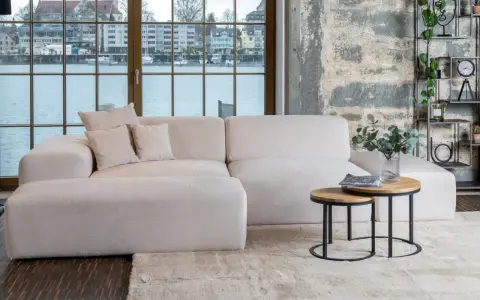 Un tavolino rotondo in legno e metallo con riviste e un vaso di eucalipto: idee per cosa mettere sul tavolino del salotto.