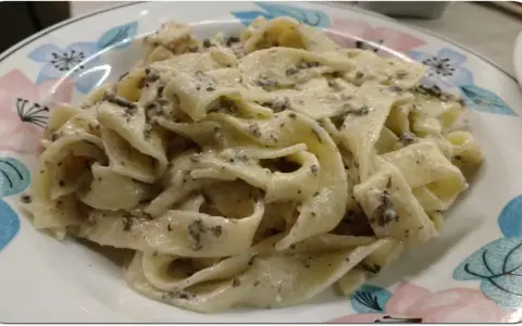 Pappardelle z kremowym sosem z mascarpone i aromatyczną pastą truflową, podane na talerzu z kwiatowym wzorem.