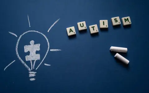 Żarówka z symbolem puzzli i litery tworzące słowo AUTISM. Wiele sławnych osób z autyzmem inspiruje nas każdego dnia.