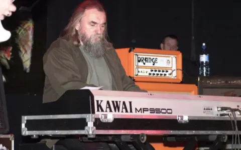 Klawiszowiec zespołu Dżem, z charakterystyczną brodą, gra na keyboardzie Kawai MP9500.