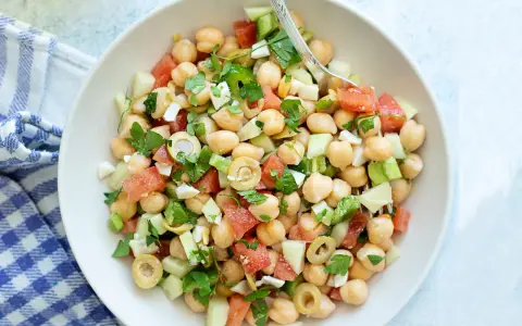 Ensalada garbanzos fresca con tomate, pepino, aceitunas y perejil. Un plato ligero y nutritivo.