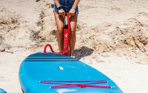 Person pumpt blaues SUP auf, um den richtigen sup luftdruck zu erreichen. Bereit für das Wasser!