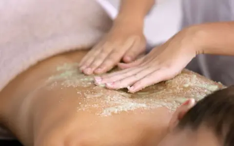 Manos expertas realizan un peeling corporal exfoliante, dejando la piel suave y renovada.