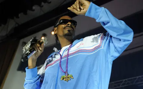 Snoop Dogg w błękitnej bluzie z naszyjnikiem, trzymający mikrofon. Ile pali? Tego nie wiemy, ale na pewno daje czadu na scenie!