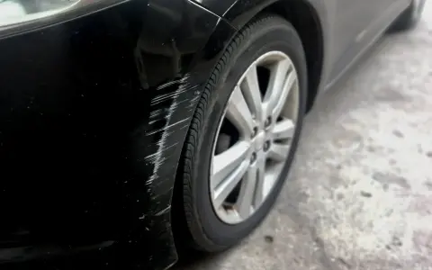 Scratches mar the black paint on a car's fender. Learn how to get scratches out of black car paint to restore its shine.