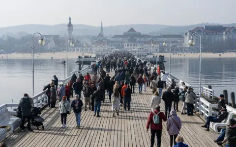 Tłumy ludzi spacerują po drewnianym molo w Sopocie. Czy molo w Sopocie jest płatne? Tego dnia wejście było darmowe, co przyciągnęło wielu turystów.