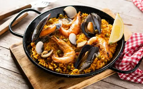 Pyszna paella z owocami morza, idealna do przygotowania z ryżem bomba. Krewetki, małże i cytryna dopełniają danie.