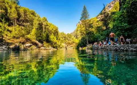 Un refrescante charco del aceite, rodeado de vegetación exuberante y rocas, con gente disfrutando del día.