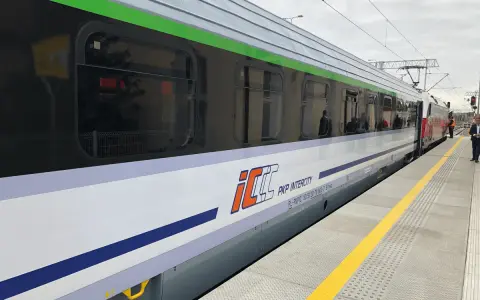 Pociąg PKP Intercity z charakterystycznym logo eic a ic stoi na peronie.