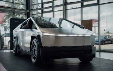 Tesla Cybertruck w salonie Tesli, z widokiem na ulicę przez okno.